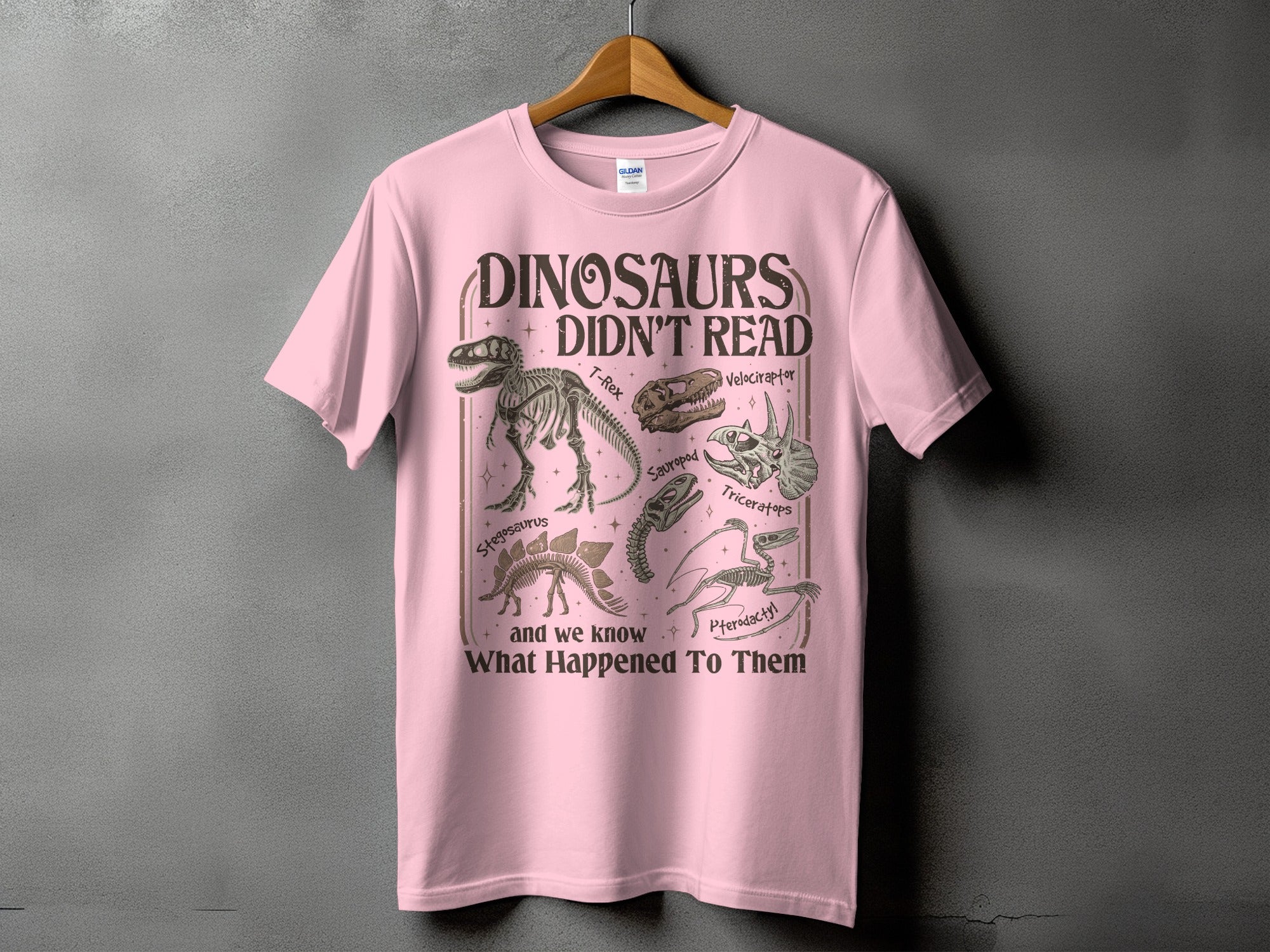 Pink t-shirt with "Dinosaurs Didn't Read" and dinosaur skeletons.