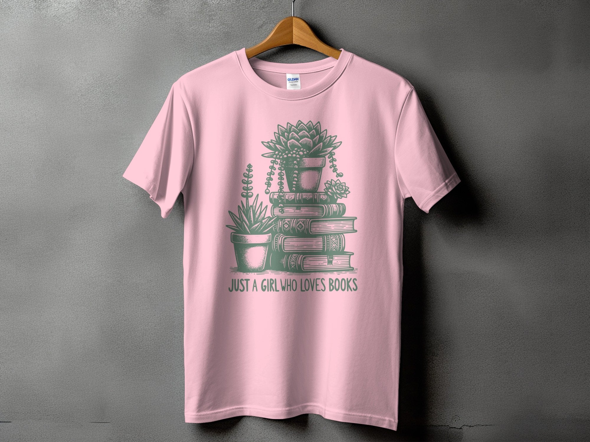 Pink t-shirt with green graphic of potted plants stacked on books and text "JUST A GIRL WHO LOVES BOOKS".