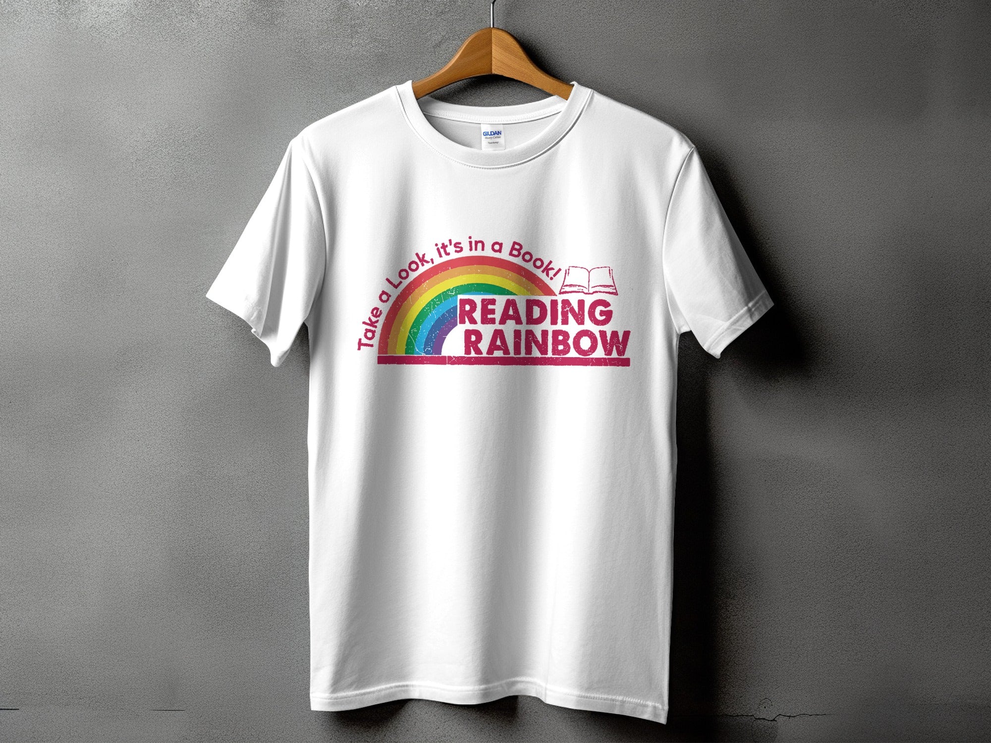 White t-shirt with "Take a Look, it's in a Book! Reading Rainbow" graphic and open book.