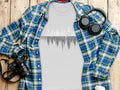 Grey t-shirt with forest and bear graphic, framed by plaid shirt, headphones, and camera.