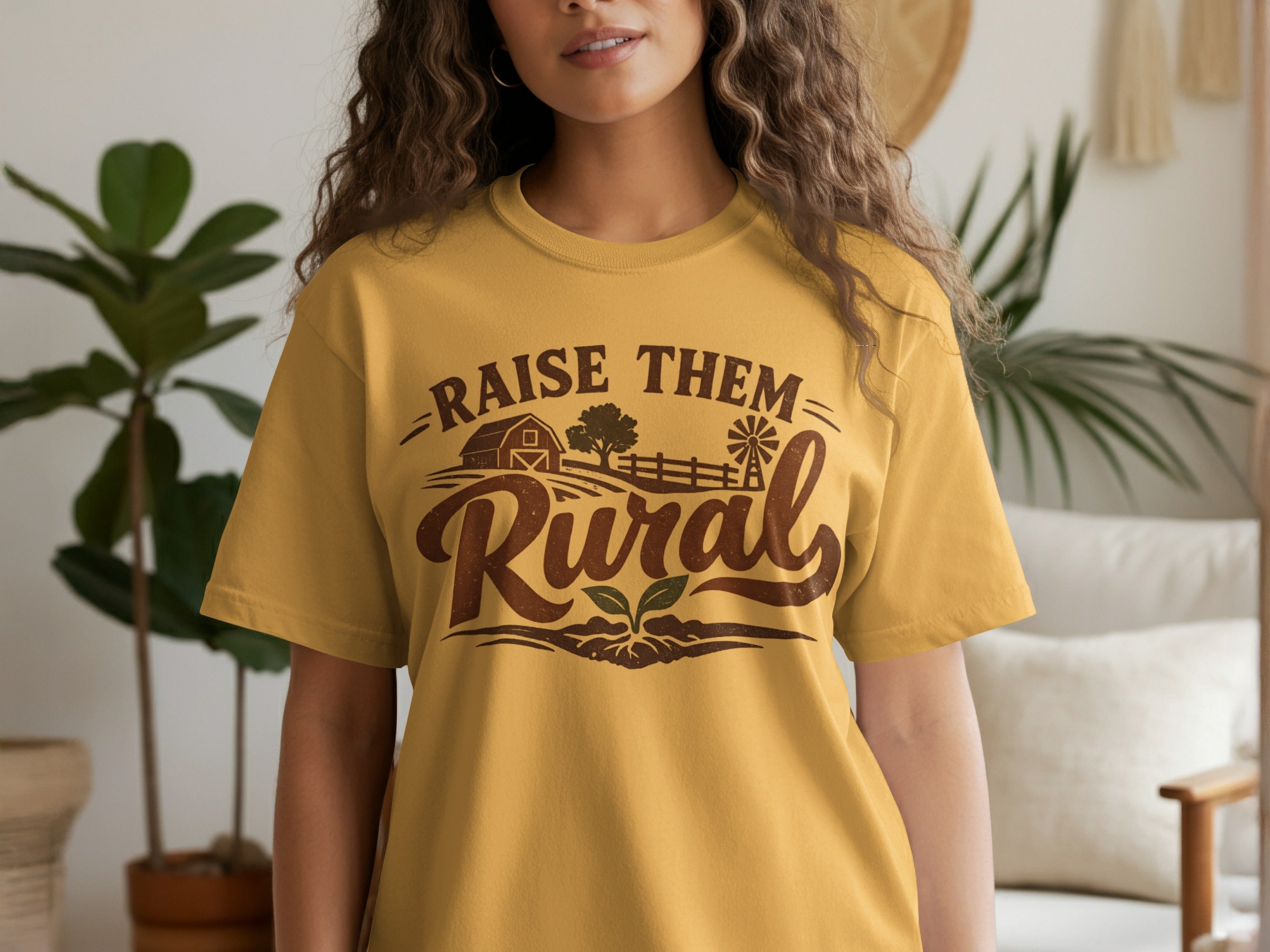 Mustard yellow t-shirt with brown graphic: "Raise Them Rural" with barn and windmill.