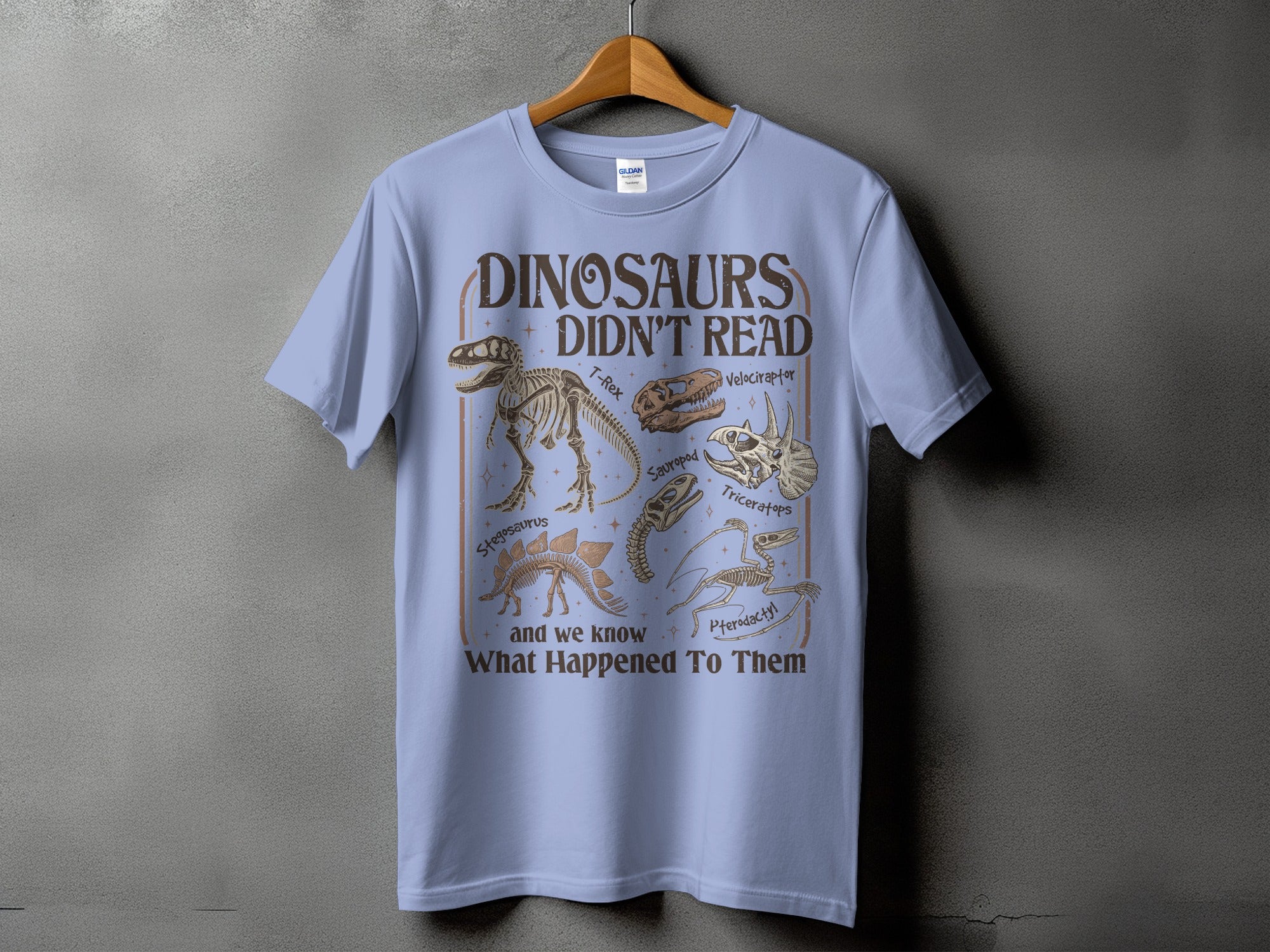 Dinosaurs Didn't Read graphic tee featuring fossil skeletons and text.