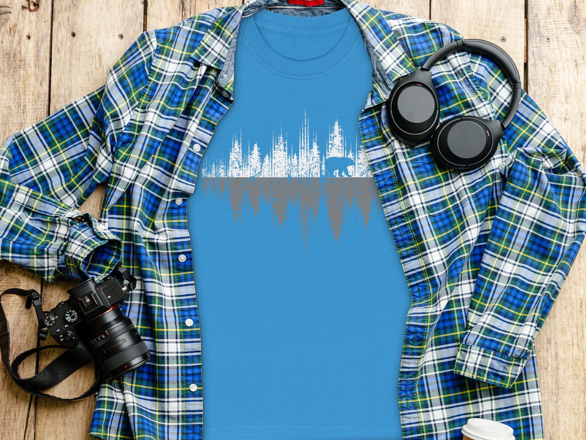 Blue t-shirt with a white and gray silhouette of a bear and forest.