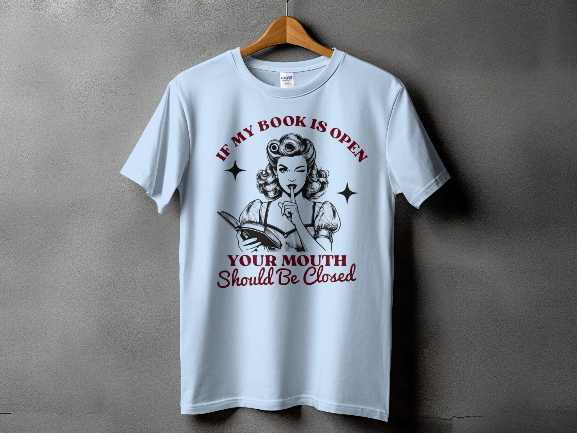 Light blue t-shirt with a graphic of a woman reading and text about books.