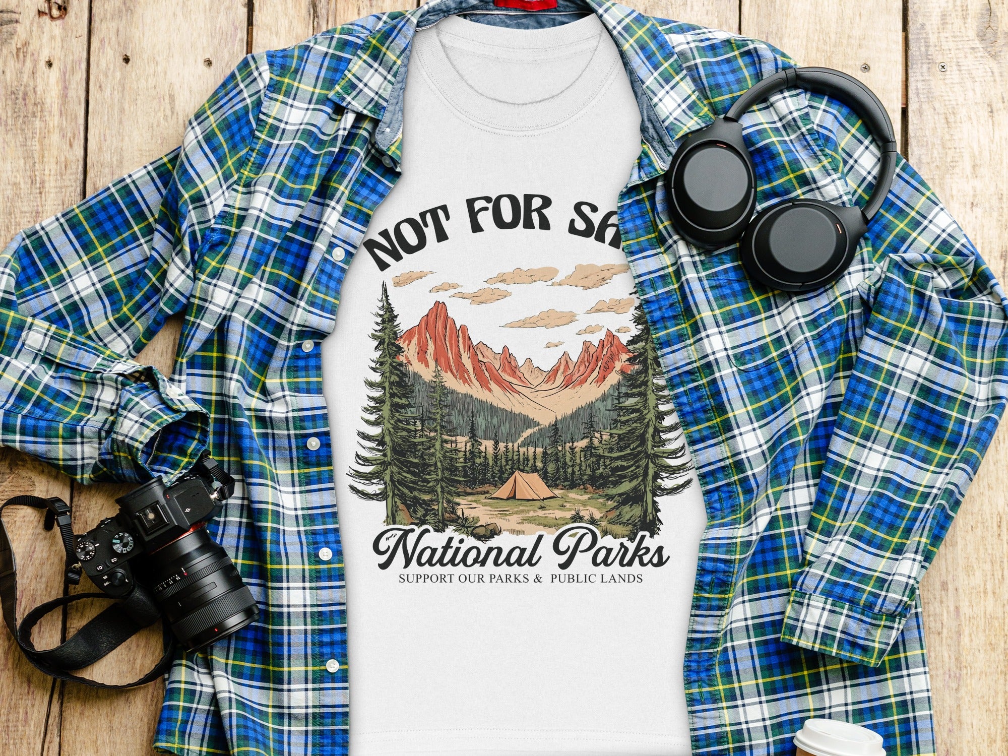 White t-shirt with "NOT FOR SA National Parks" graphic, layered over plaid shirt.