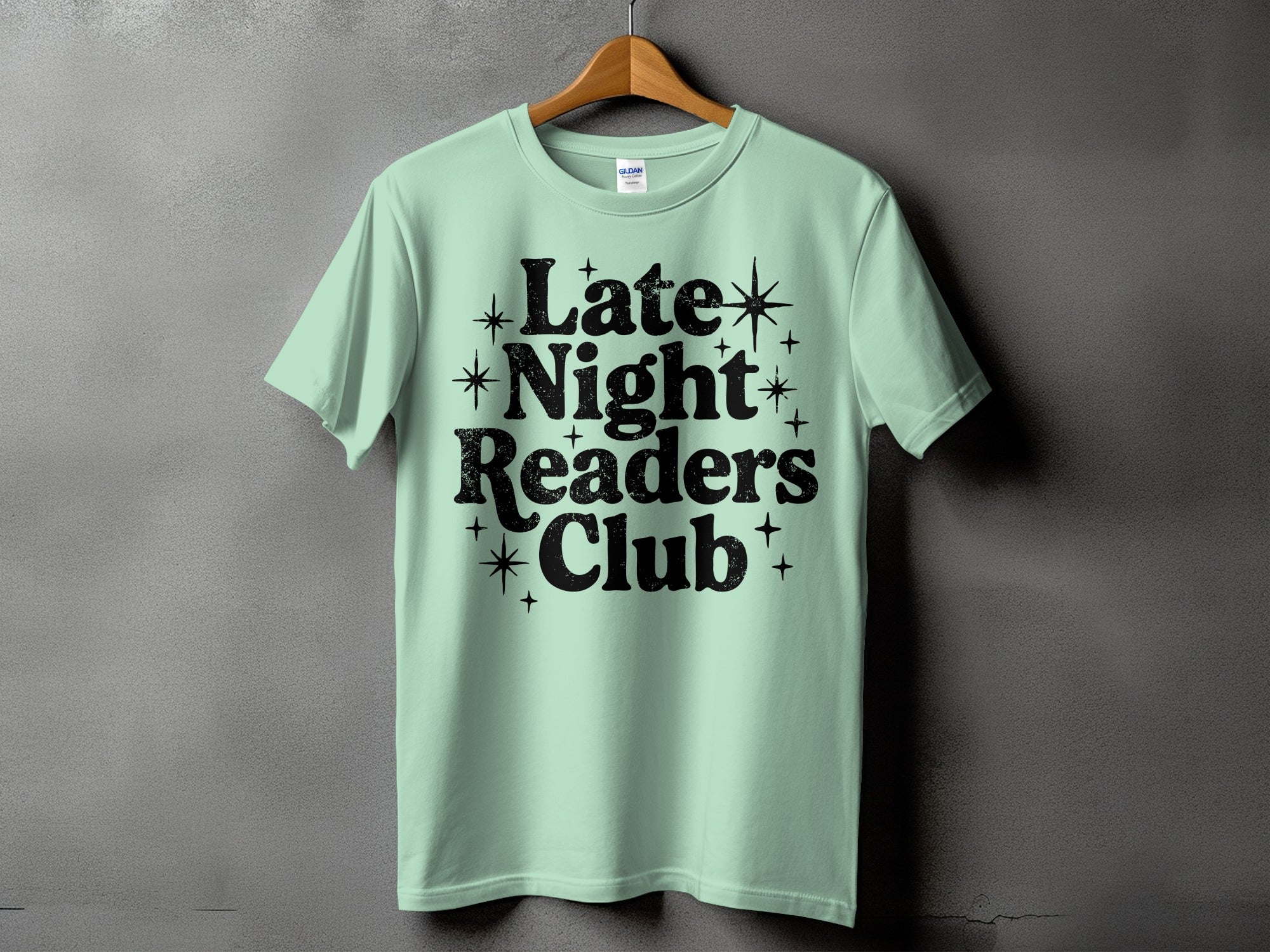 Light mint green t-shirt with black text "Late Night Readers Club" and stars.