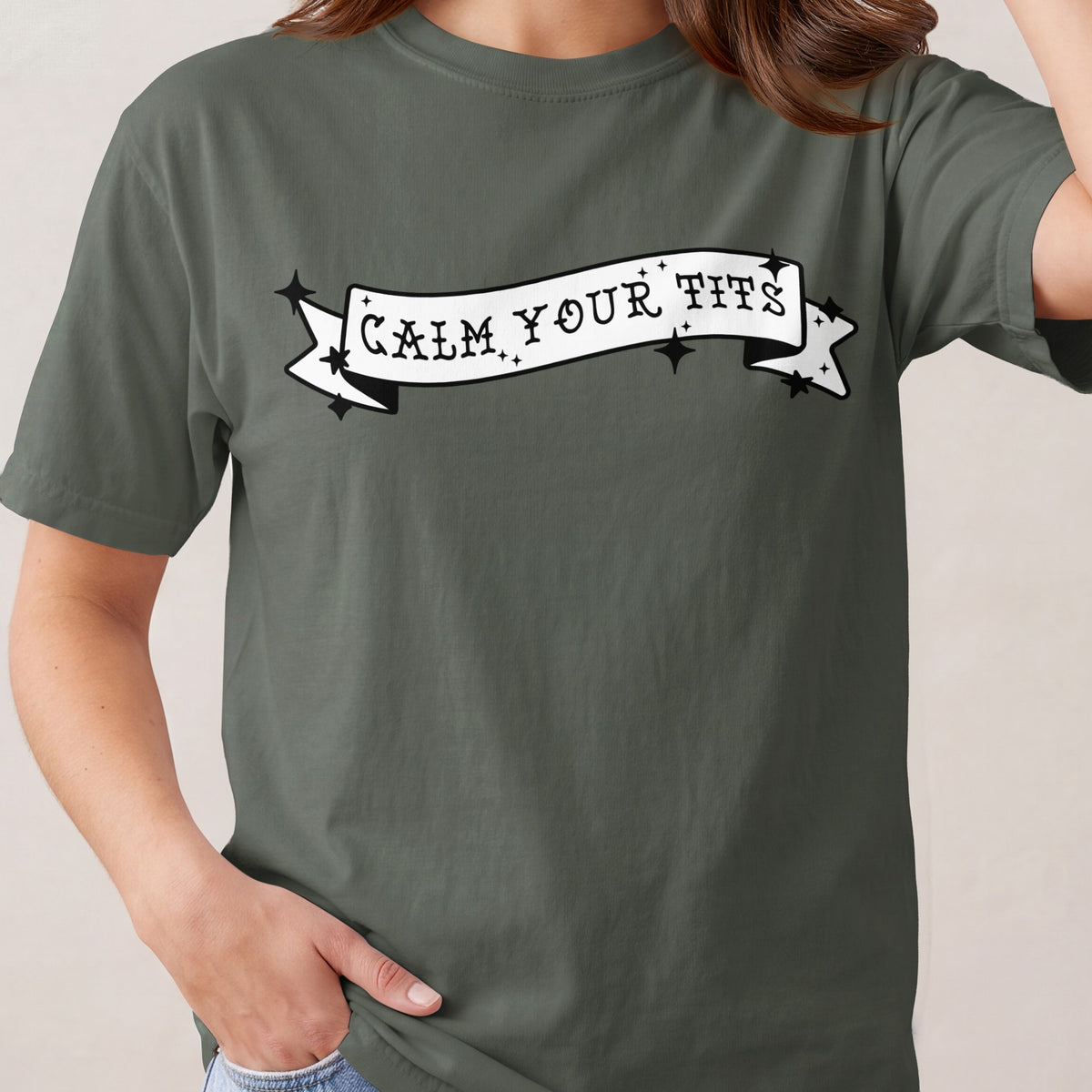 Green t-shirt with white banner graphic reading "CALM YOUR TITS".
