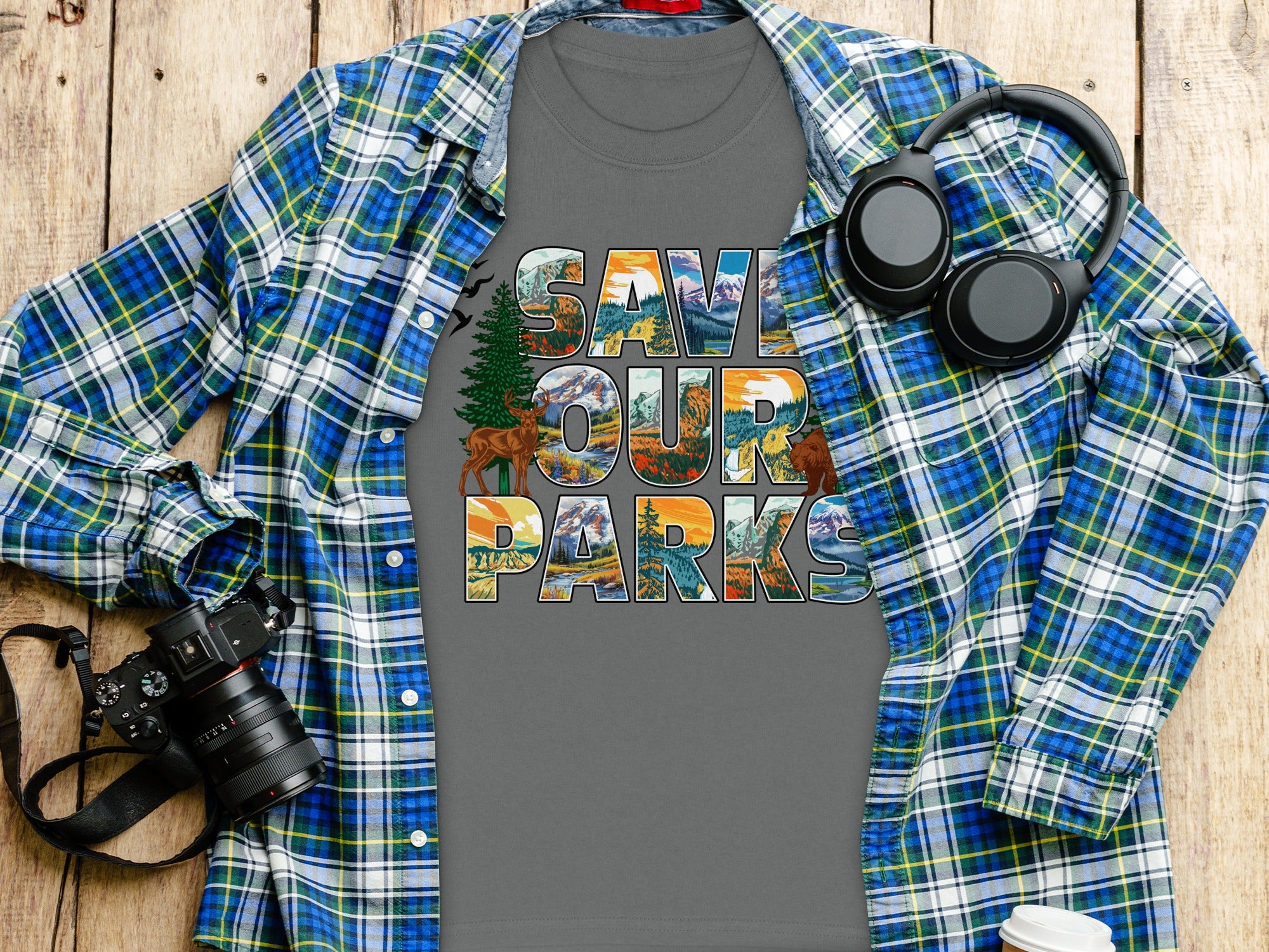 Save Our Parks graphic t-shirt with landscapes in text, plaid shirt, camera, and headphones.